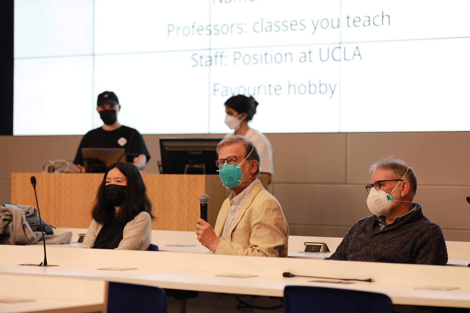 A photograph from the Spring 2022 Computer Science Town Hall. Professor Eggert is introducing himself and other professors are sitting beside him.